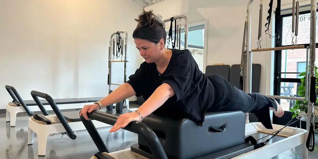 Pilates Instructor performing Swan on Reformer