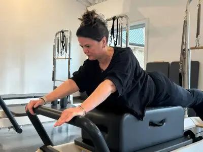 Pilates Instructor performing Swan on Reformer