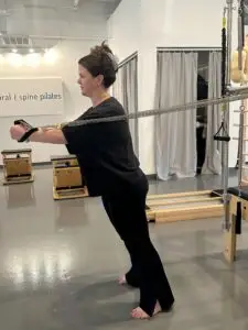 Pilates Instructor performing Standing Arms Facing Away on Cadillac