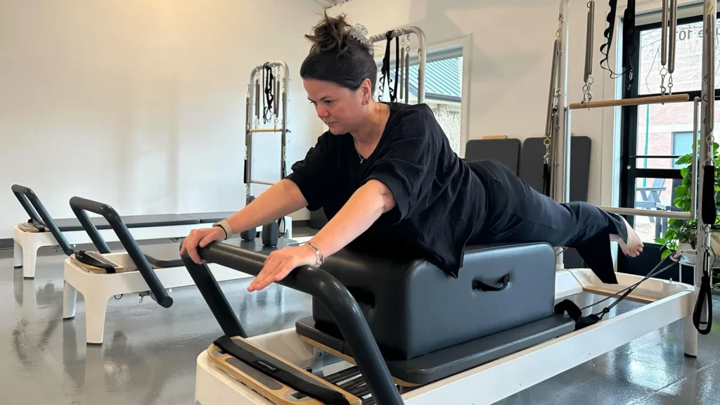 Pilates Instructor performing Long Box Swan on Reformer