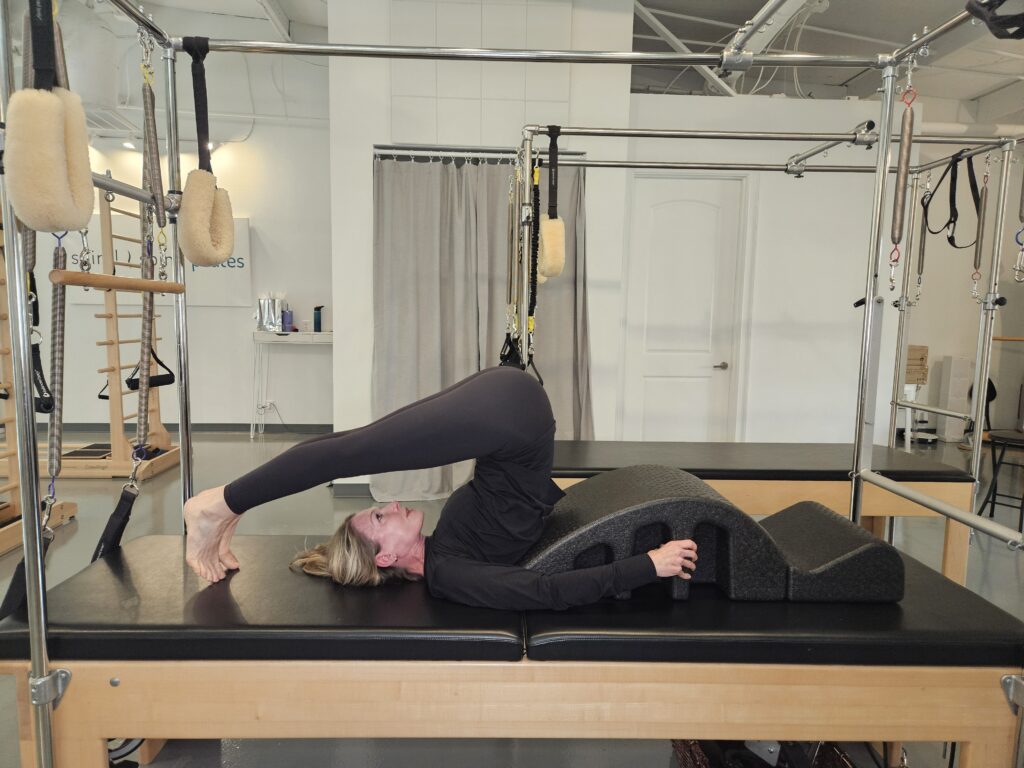 Pilates Instructor doing flexion exercise called Rolloveron Arc